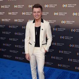 Shawn Hook posing on carpet in front of a wall that says 'Mercy for Animals.'