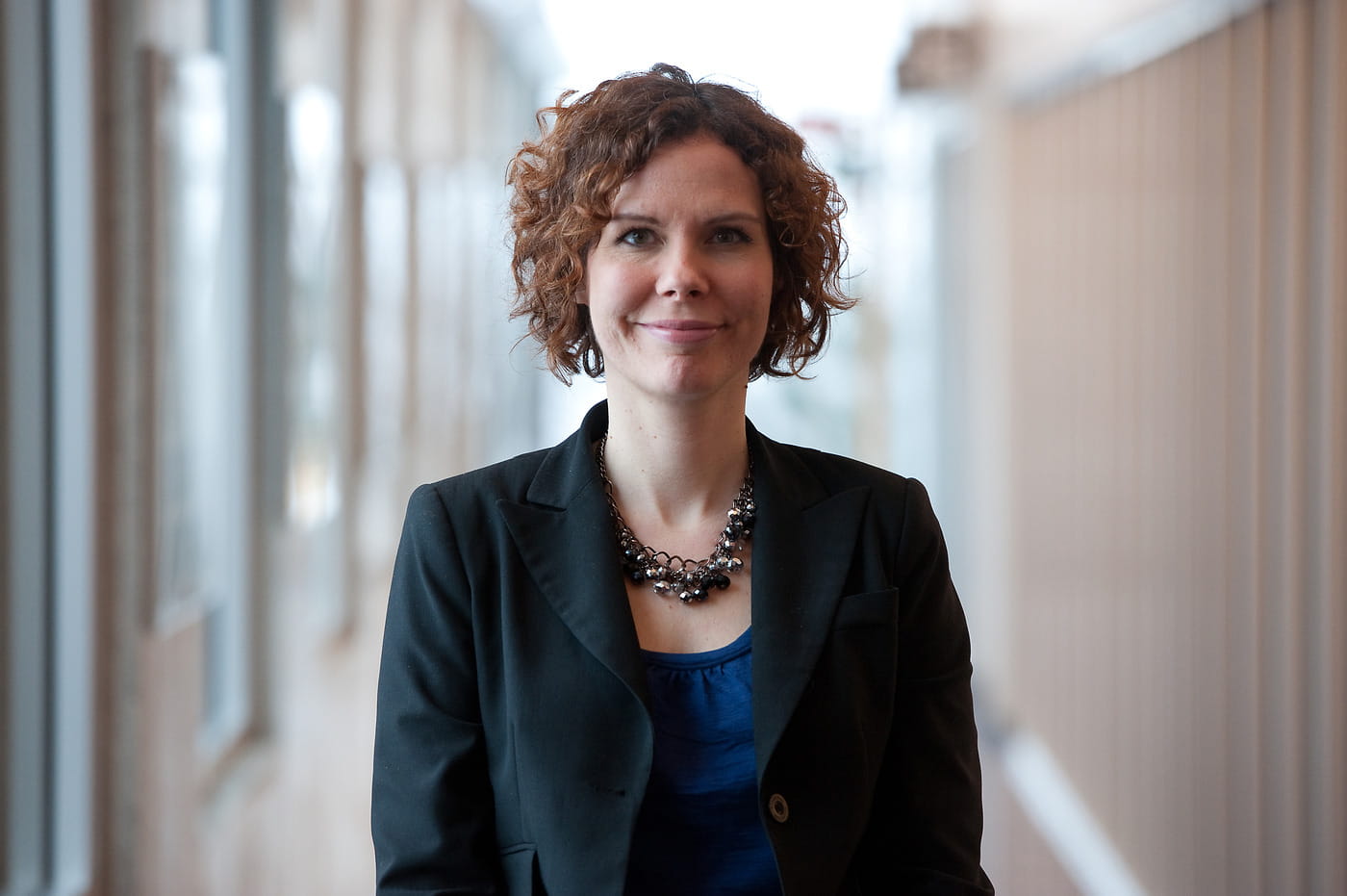 Sophie Lebel, a researcher wearing a black jacket, is standing in a corridor.