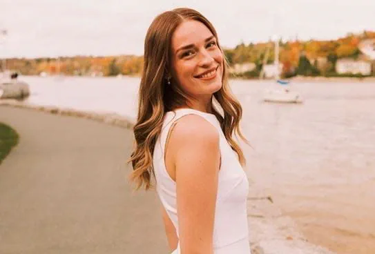 Ruby, turning around and smiling on a walkway overlooking a lake.