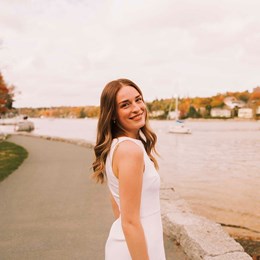 Ruby, souriant en se retournant pour faire face à l’appareil photo, sur une voie piétonne au bord d’un lac.