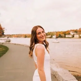 Ruby, turning around and smiling on a walkway overlooking a lake.