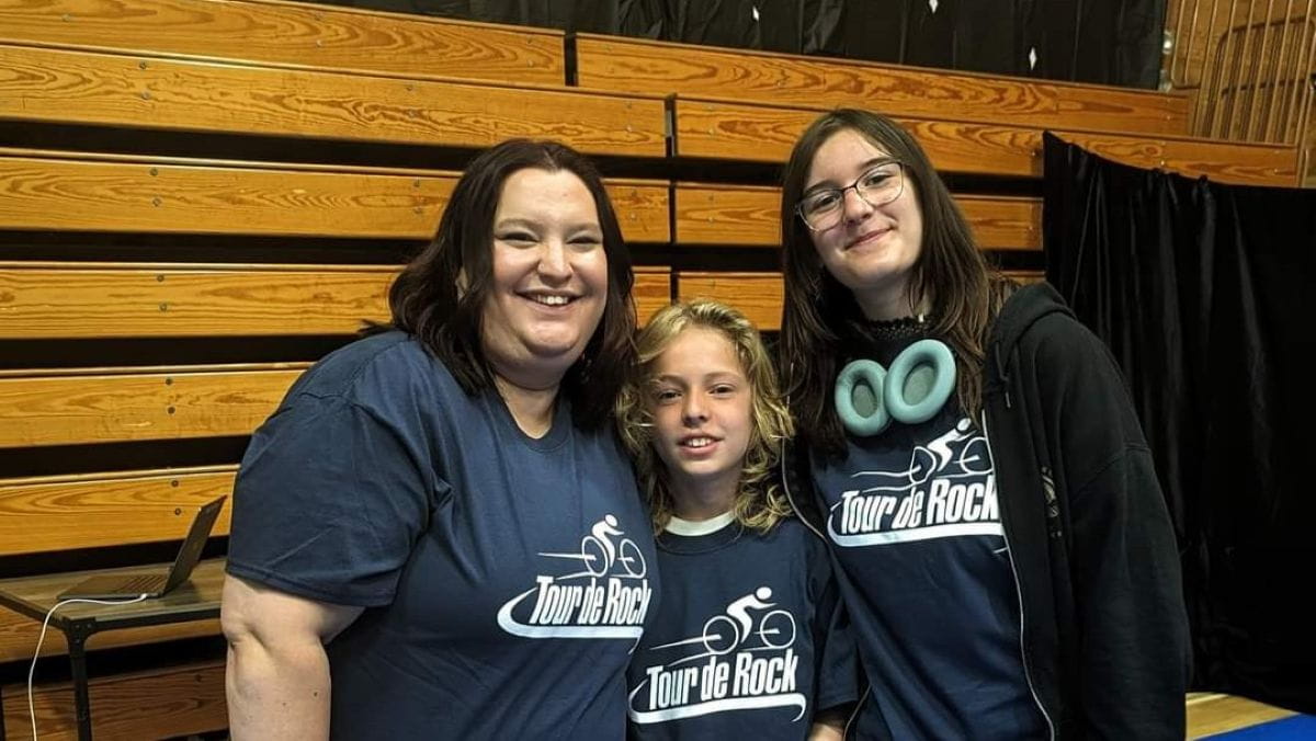Kyla pose avec ses enfants lors d’un événement Tour de Rock. Ils portent tous un t-shirt de Tour de Rock.