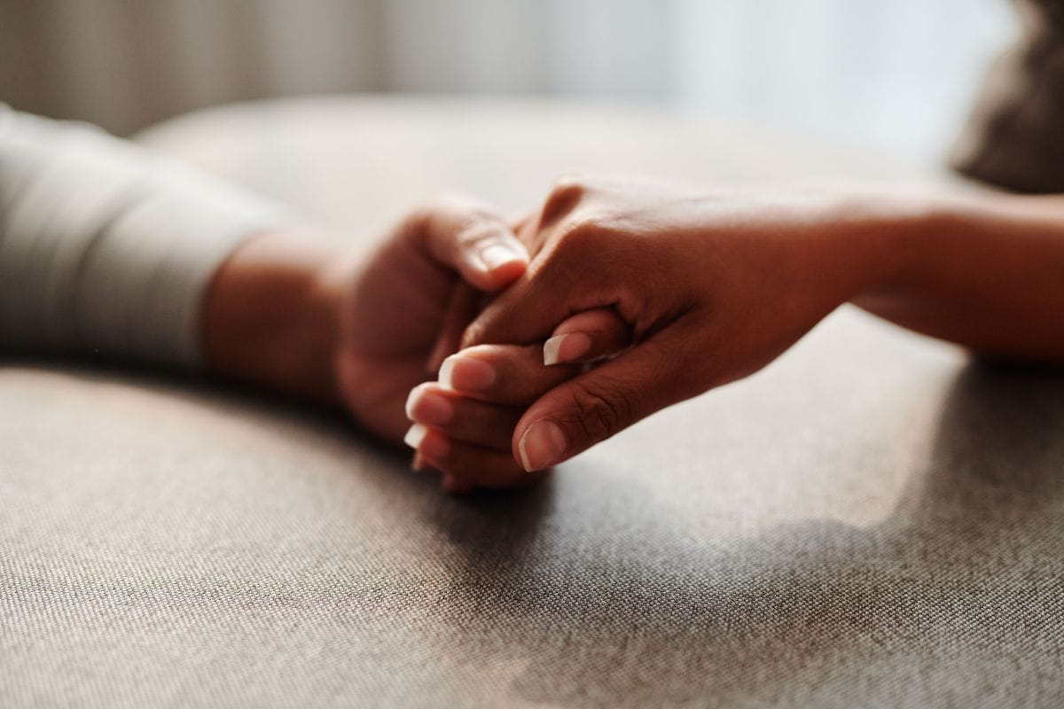 Close-up of two hands gently clasped together.