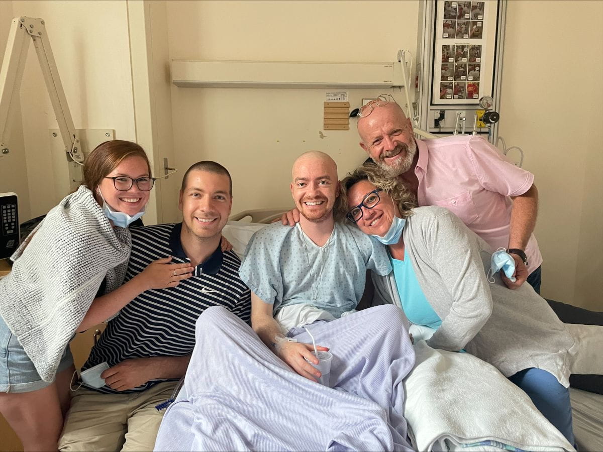 Anthony Vallée is seated in a hospital bed, surrounded by his family. 