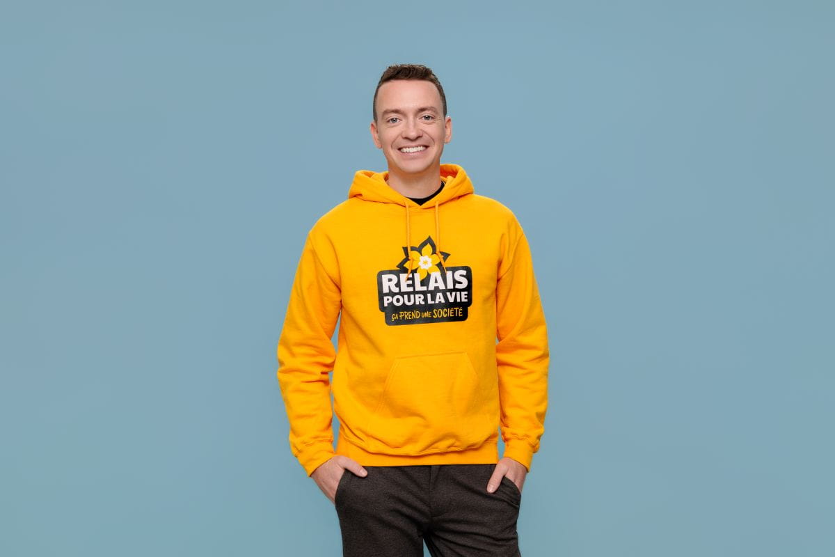 Anthony Vallée wears a Relay For Life hoodie as he smiles at the camera. 
