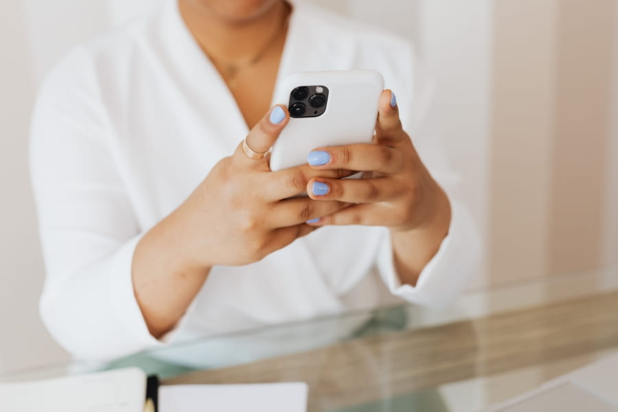 A person sitting at a table and holding a cell phone.