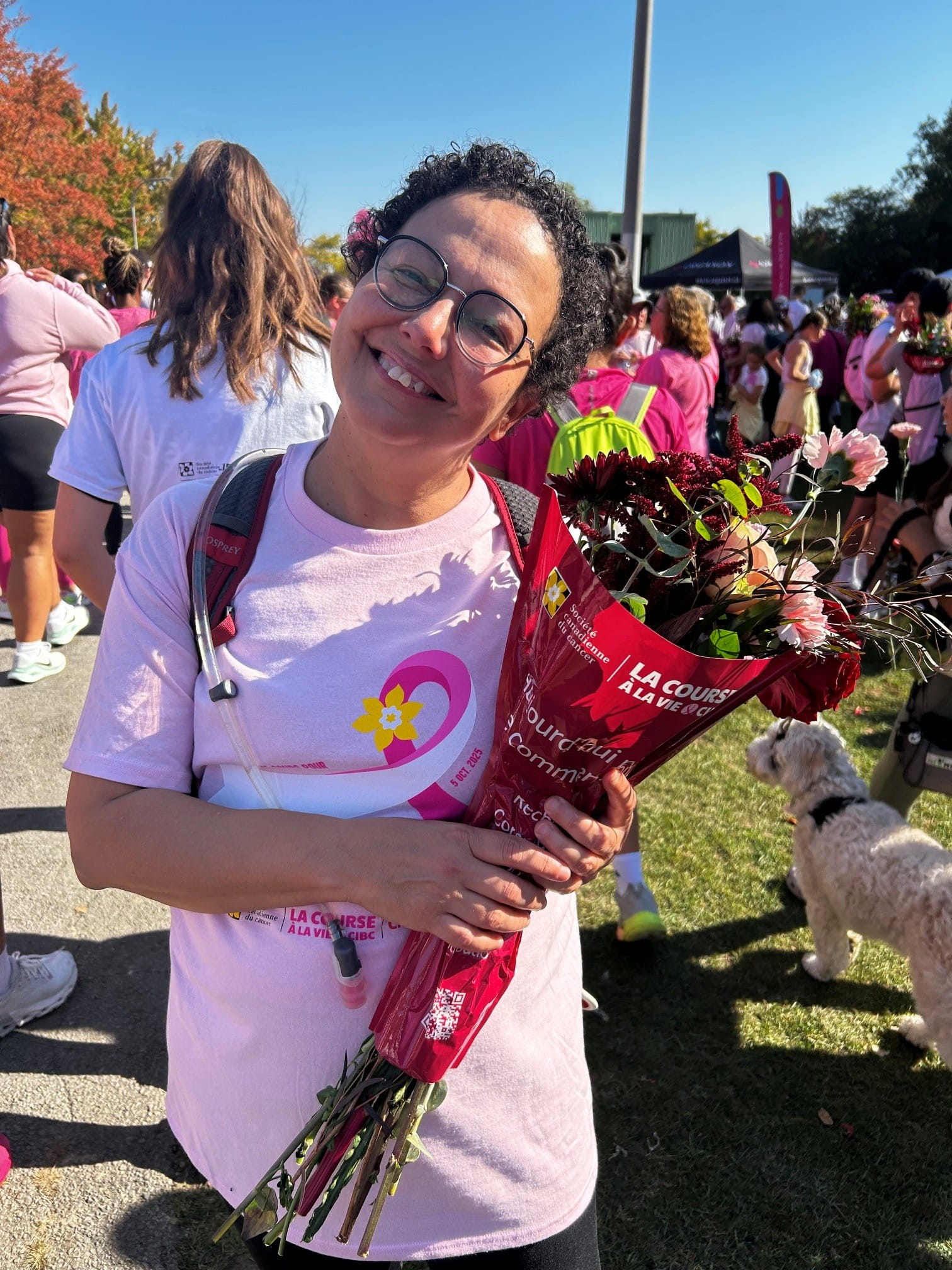 Assia Meddane tient un bouquet de fleurs à l’extérieur lors de la Course à la vie CIBC, entourée de participants.