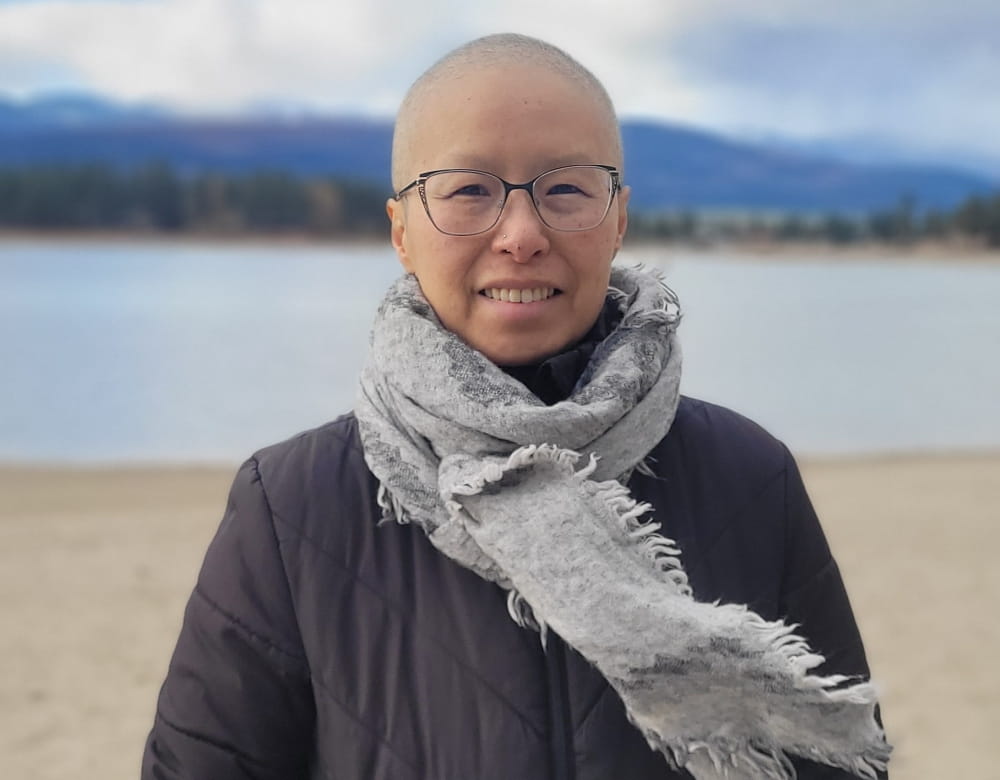 Rita Pak standing on a beach after losing her hair.