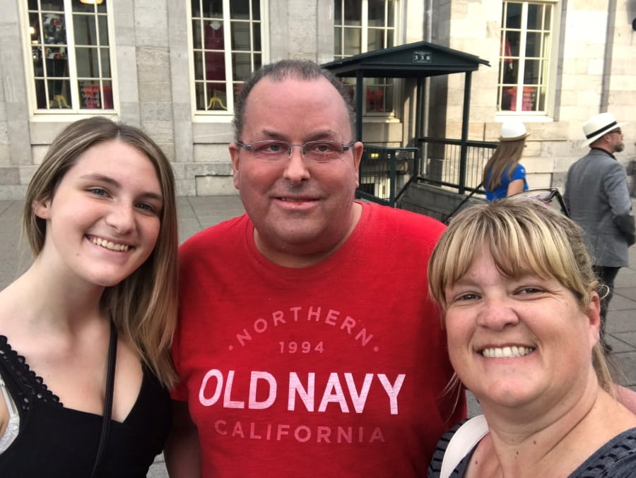 Chantal’s daughter, Chantal’s husband and Chantal standing in front of a building.
