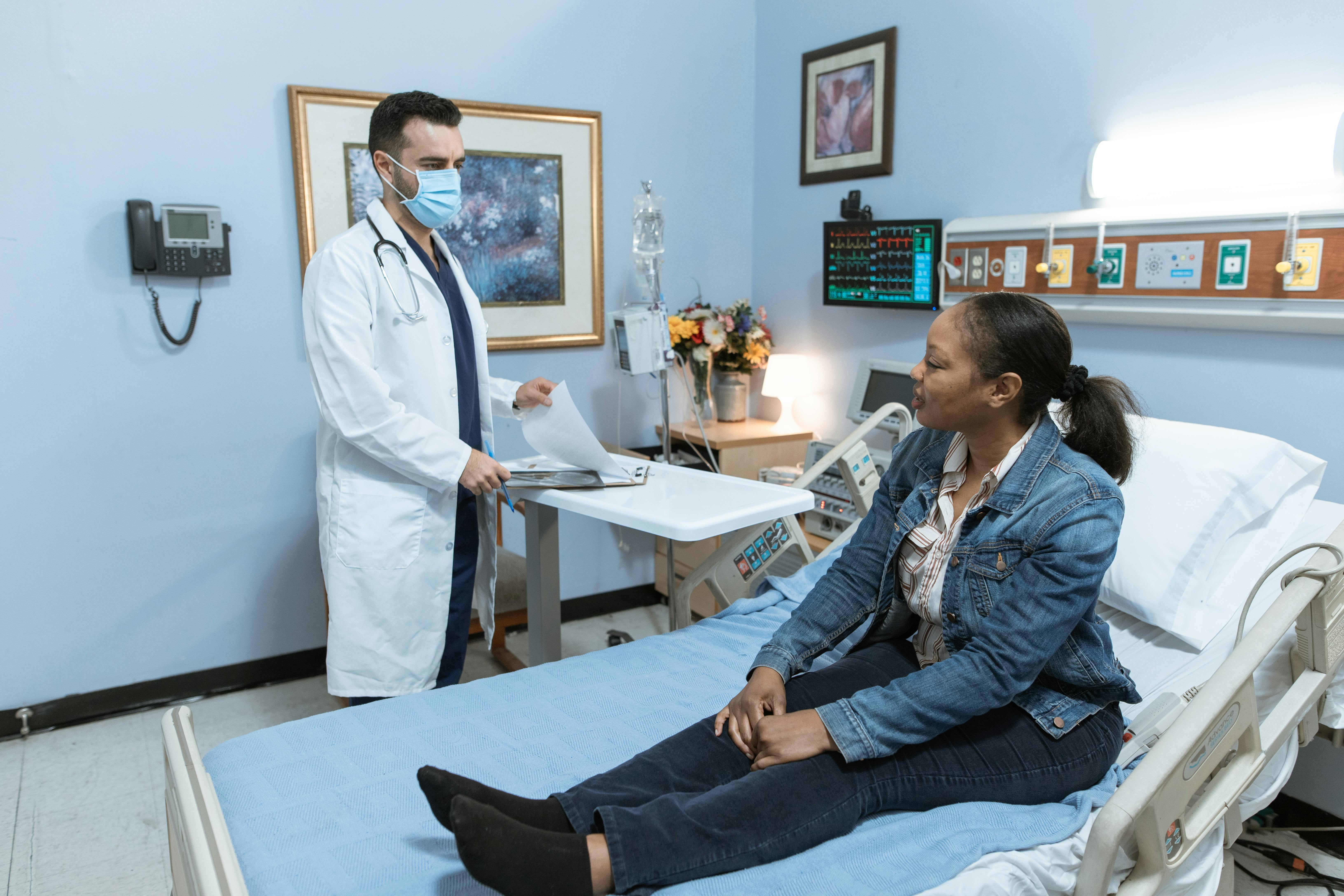 A doctor standing in front of a patient sitting on a hospital bed.