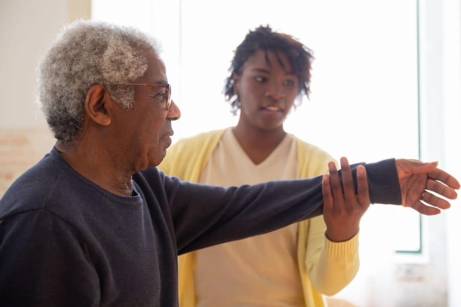 A physical therapist helping a person lift their arm.