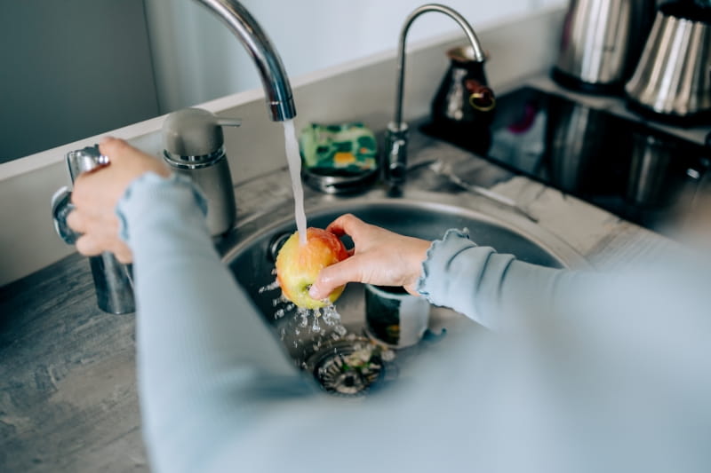 An apple being washed in the sink