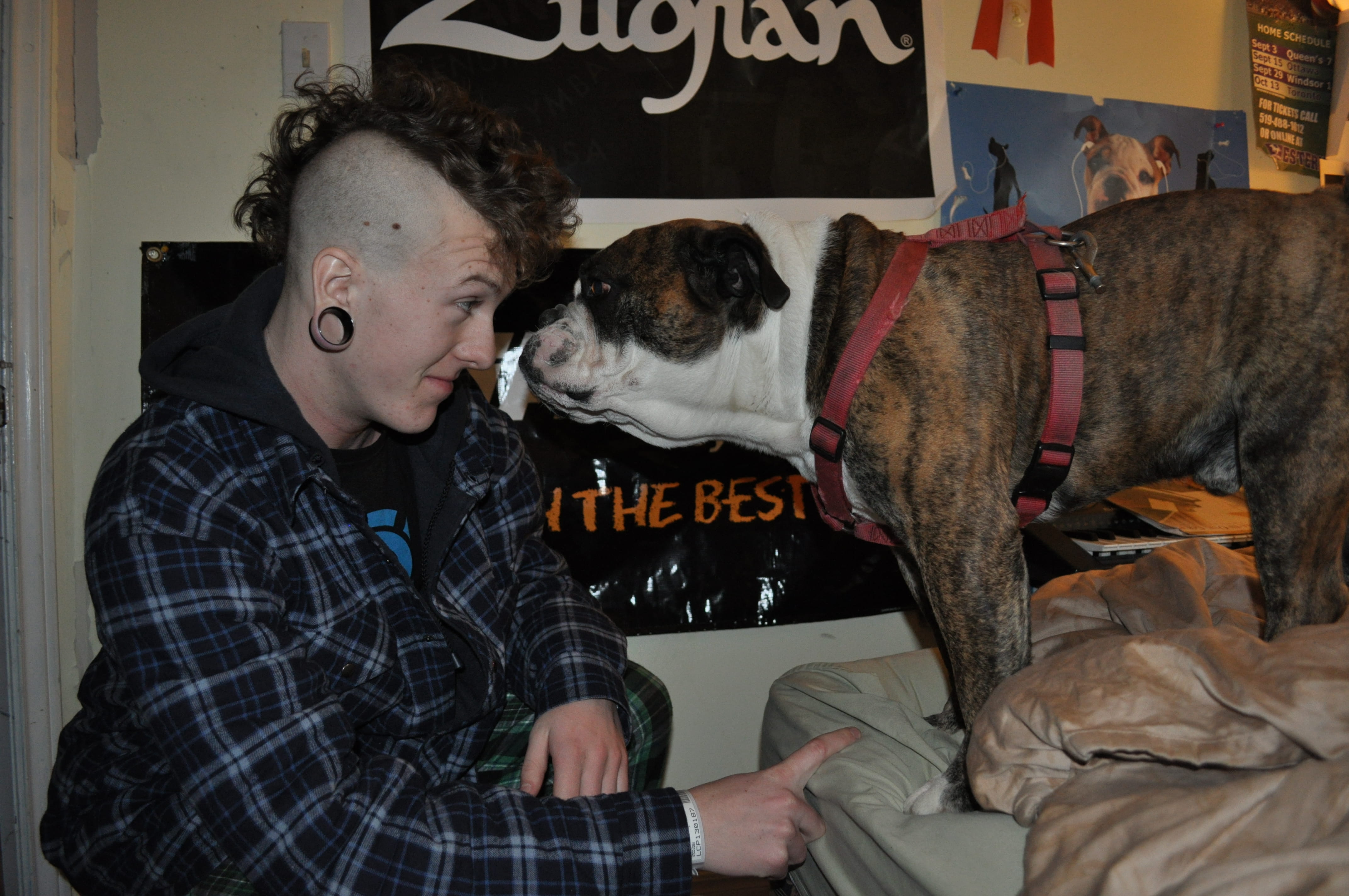 Nick leans in for a kiss from his dog. His hair is shaved on the sides. 