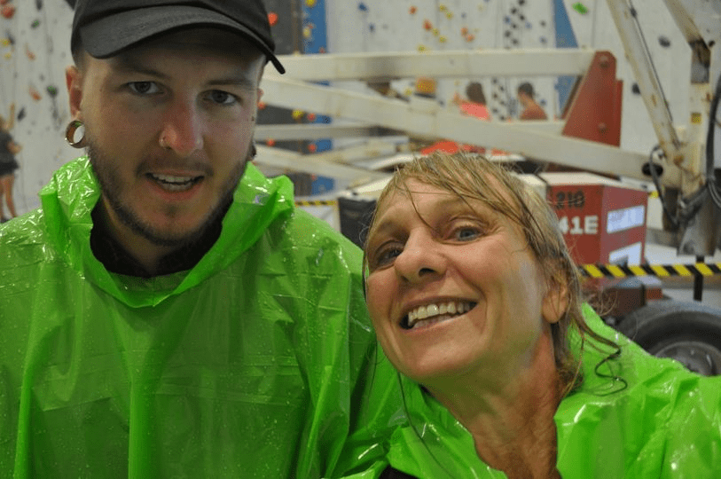 Nick et Tanja portent des imperméables, devant un mur d’escalade.
