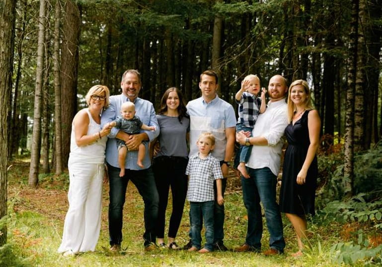 Charlie and his family posing together in a forest.