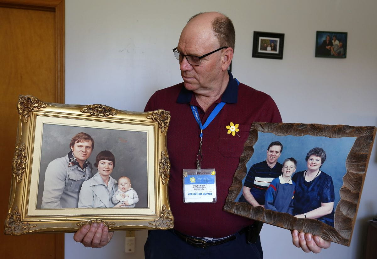 Wayne Bush tient deux photos encadrées de sa famille.