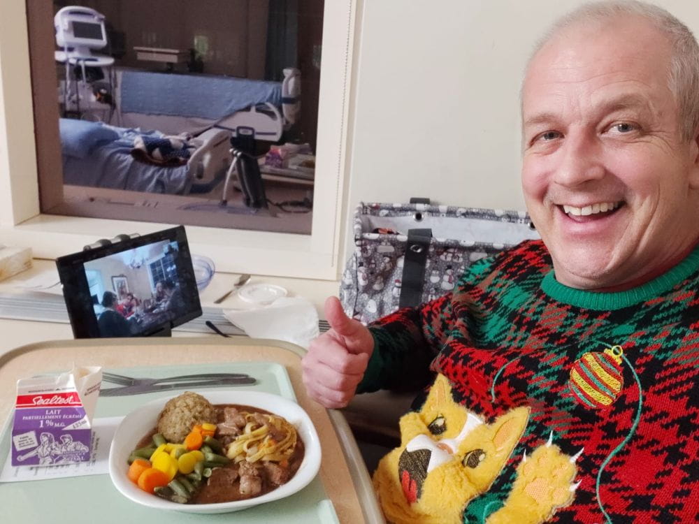 Terry takes a selfie with his dinner in hospital. He wears a Christmas sweater.