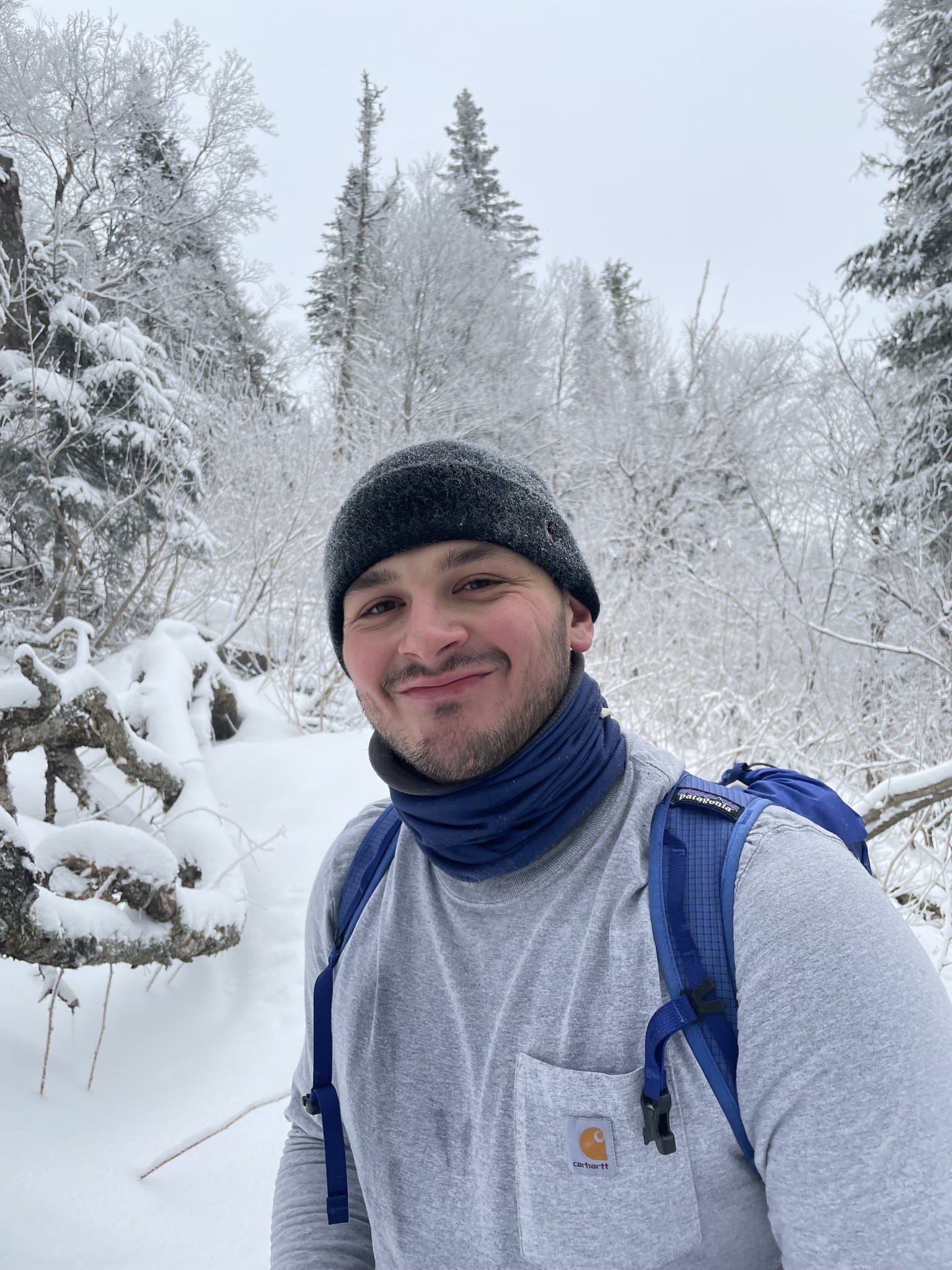 James posing outside in front of snow-covered trees.