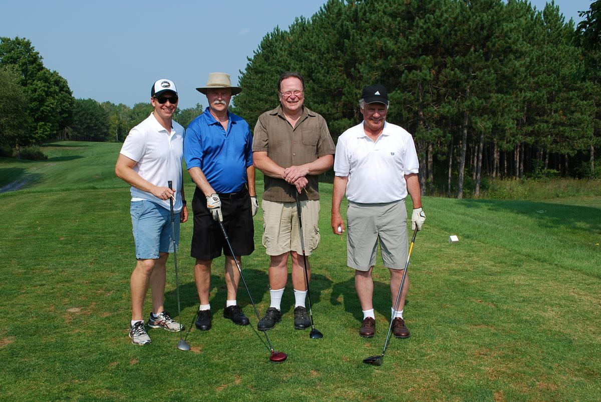 Stuart and his 3 friends stand on a golf course.