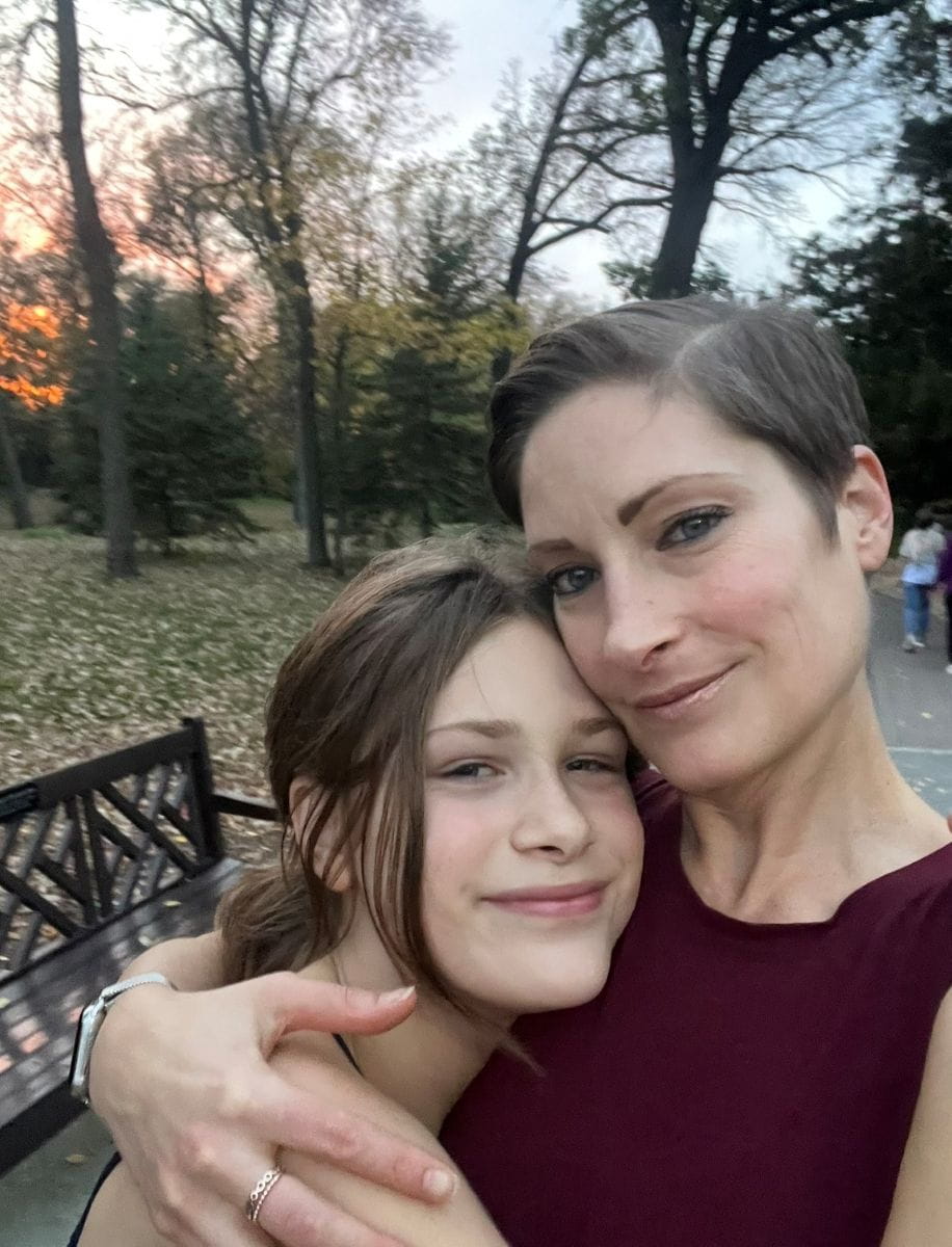 Catherine hugs her daughter while walking in the park. 
