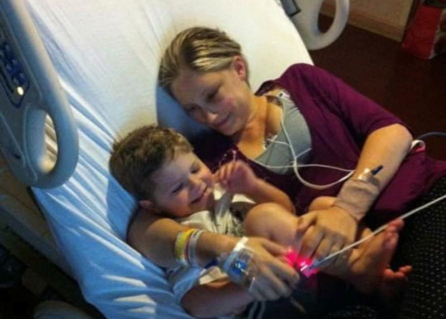 Catherine est allongée dans son lit d’hôpital avec son fils blotti contre elle.