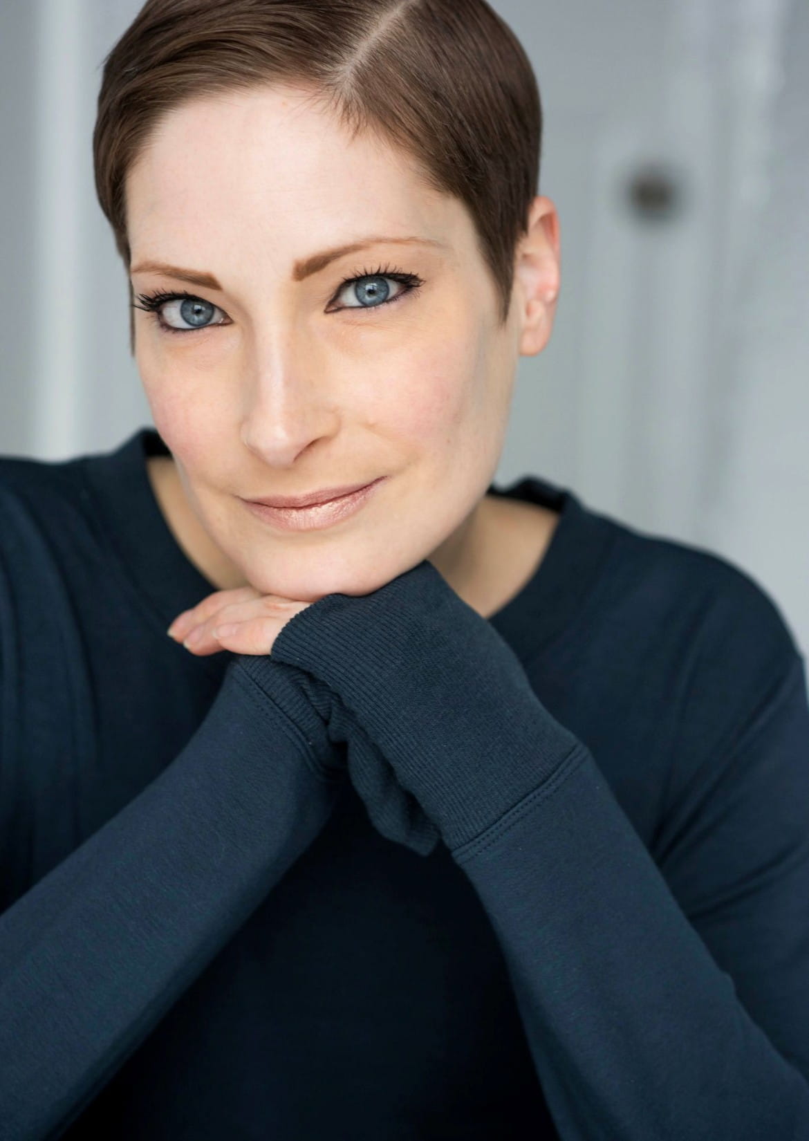 Catherine looks directly into the camera, with her chin resting on  her hands.