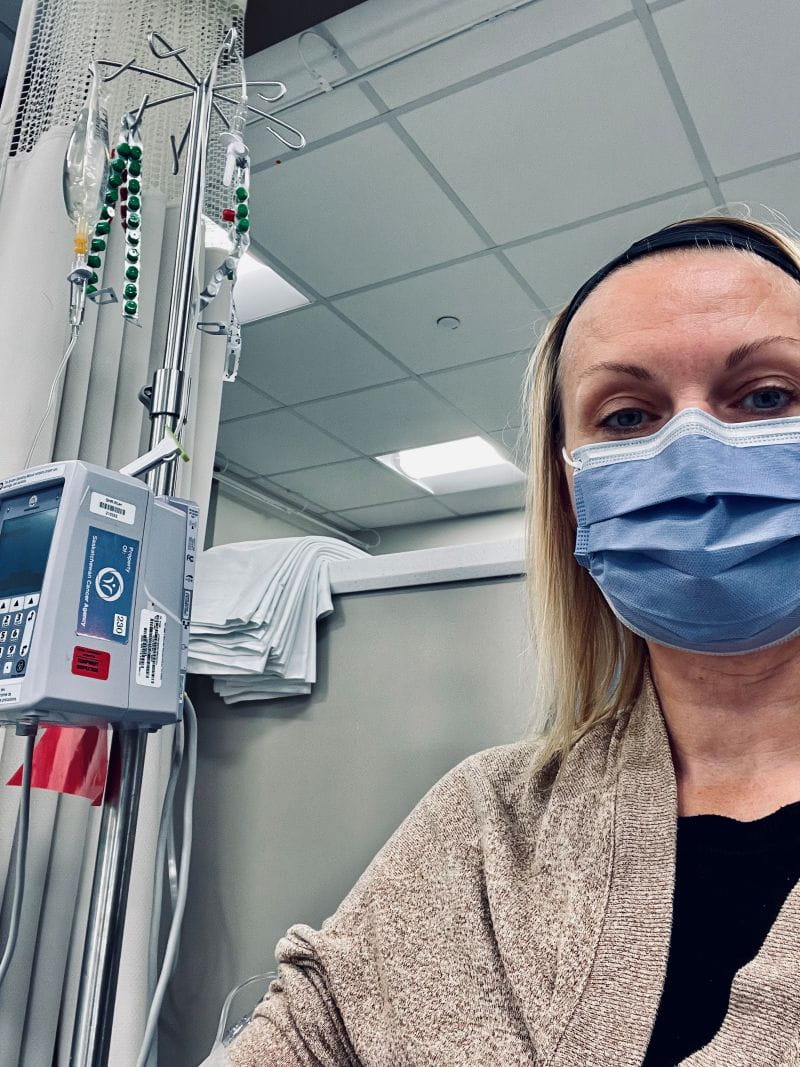 Tennille wears a blue face mask in the hospital. She is connected to a machine.