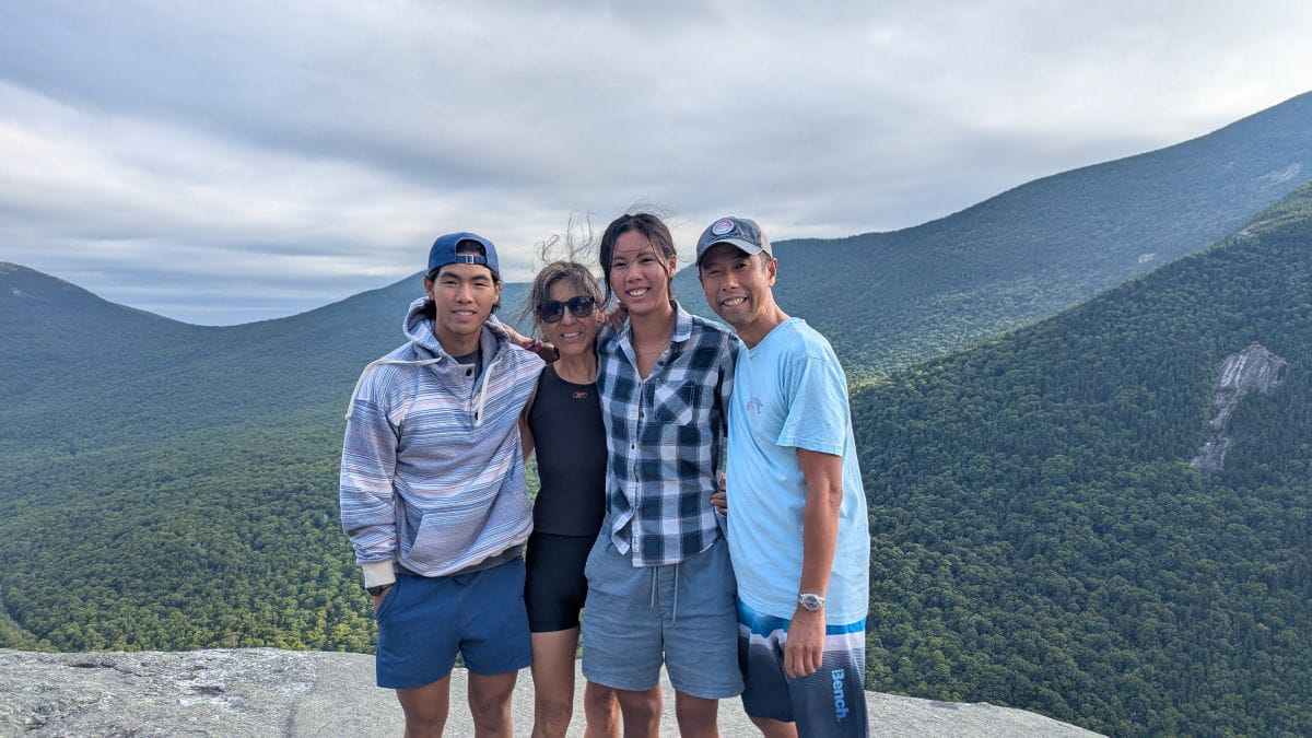 Winhan and his family pose together. There are mountains behind them.