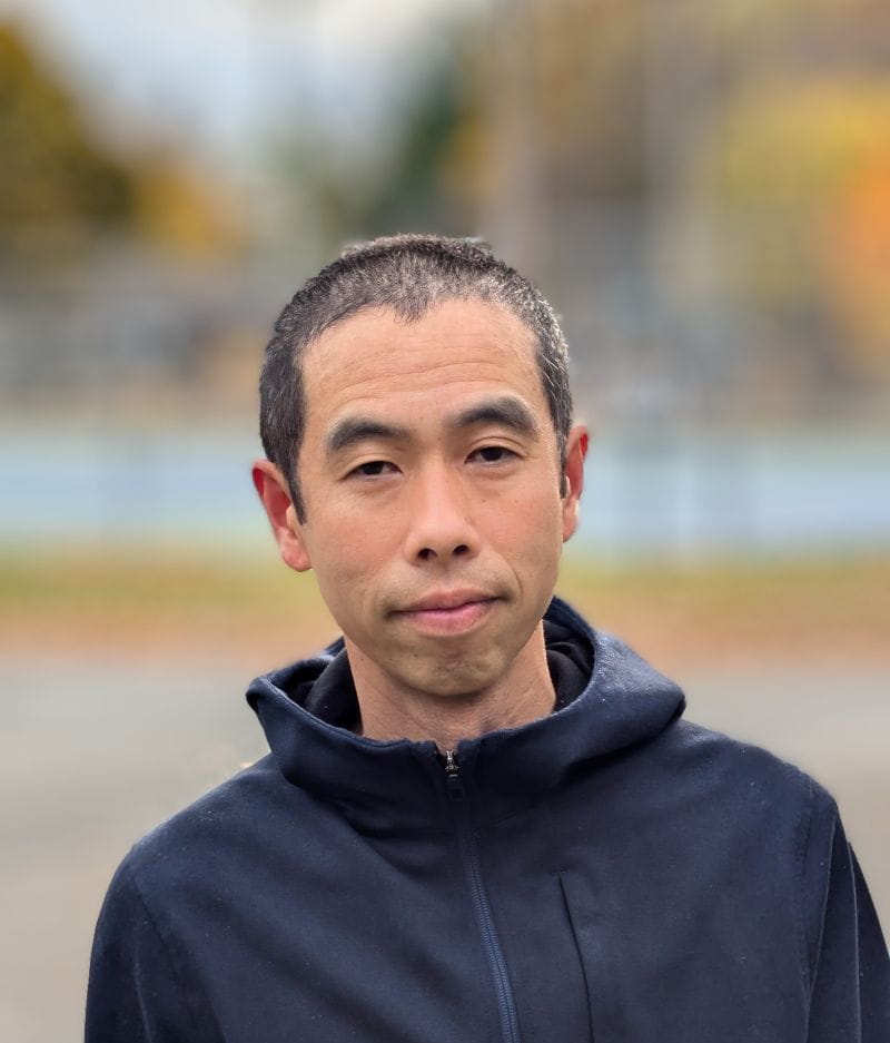 Winhan stands outside wearing a rain jacket.