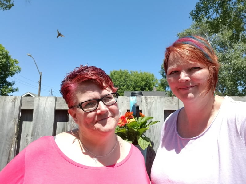 Paula Pestrin and Sandra de Haan standing together in their backyard.