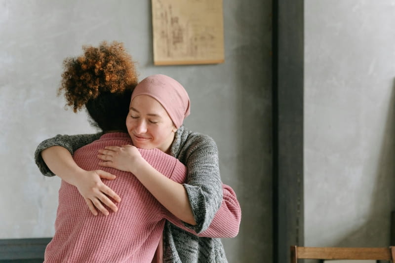 Two people hugging. One person wears a head scarf.