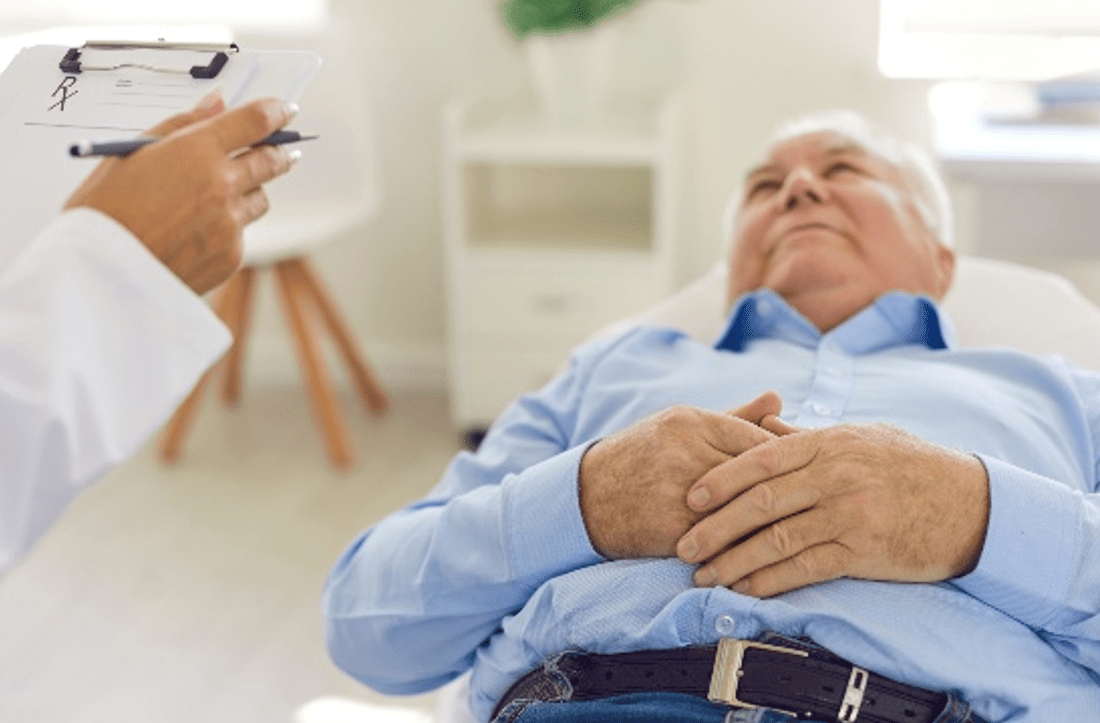 A man lying on an examination table while speaking with a healthcare professional.