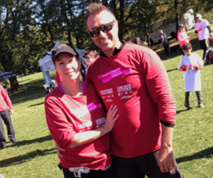 Sonia et son conjoint dehors, qui portent des t-shirts de la Course à la vie CIBC et sourient.