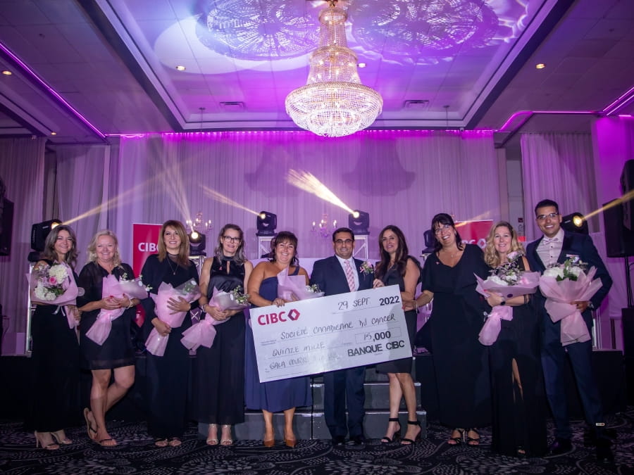 Sonia et ses collègues qui tiennent des bouquets de fleurs et posent avec un gros chèque de la CIBC.