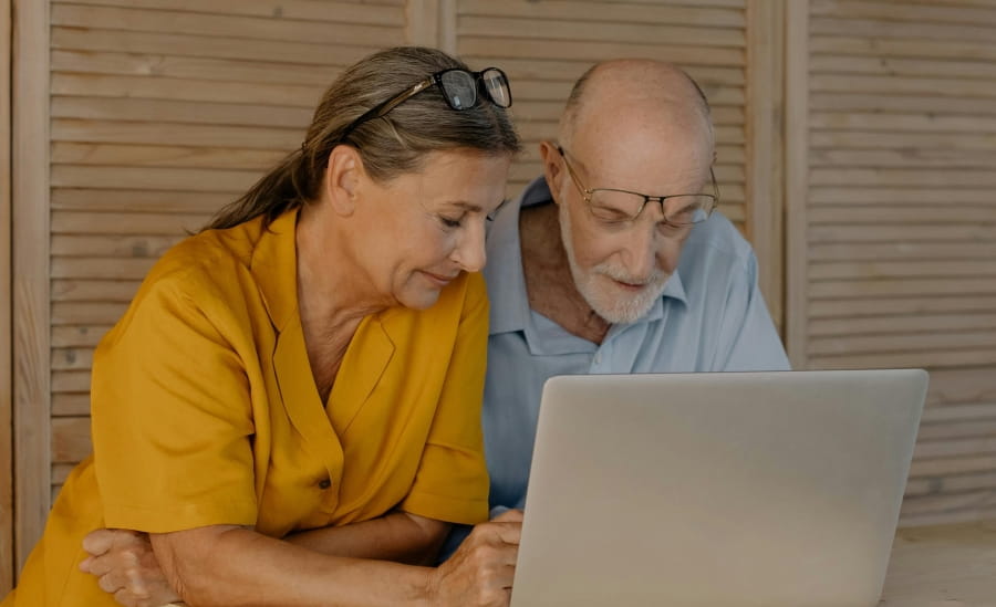 Two people leaning over a laptop.