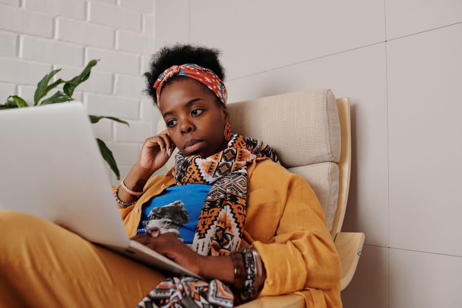 A person sitting on a chair and looking at their laptop.