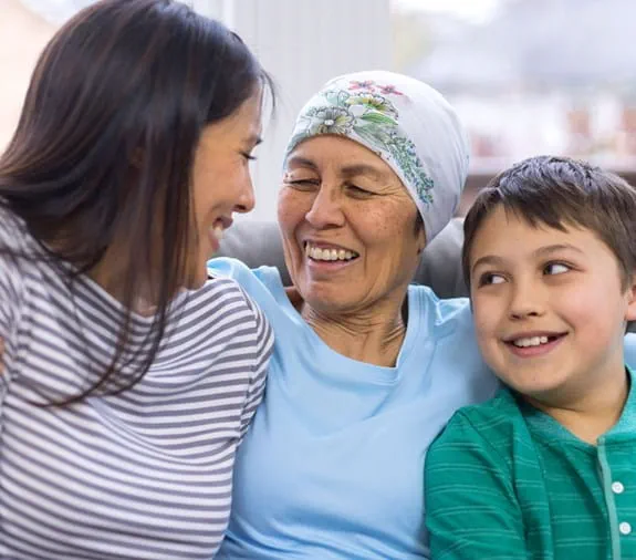 A photo of a mom sitting on a sofa with her daughter and young son.