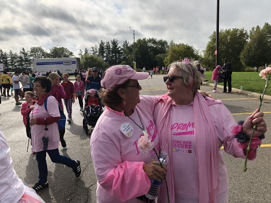 Wendy Garner standing next to a fellow CIBC Run for the Cure participant, dressed in pink while holding a flower.