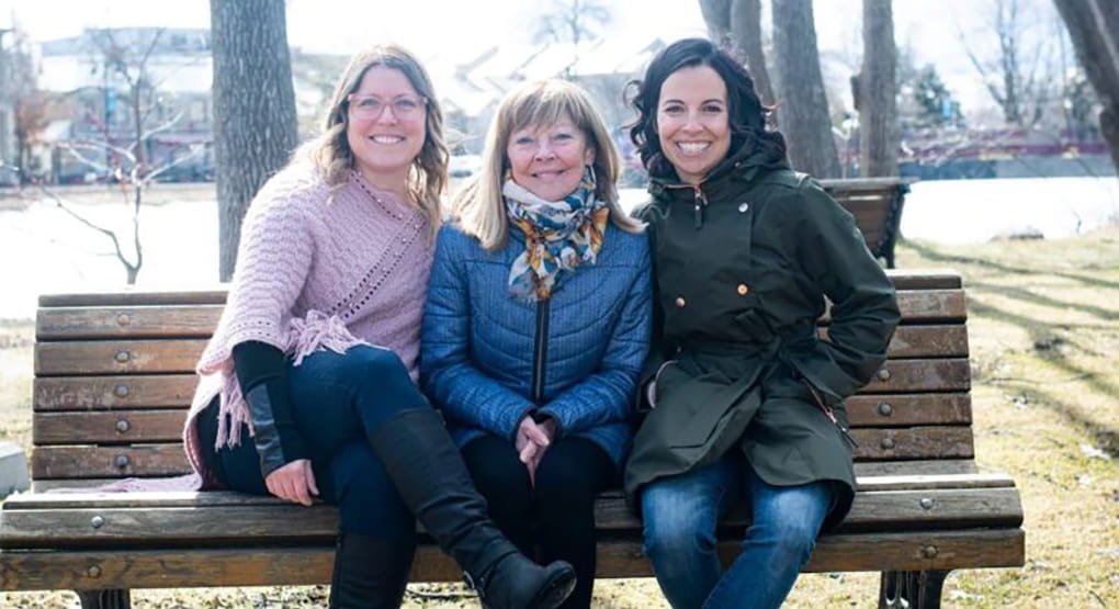 Louise-Hélène is sitting on a bench with her two daughters.