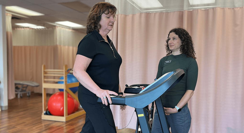 Terri Swain-Collins walking on a treadmill while her physiotherapist watches her.