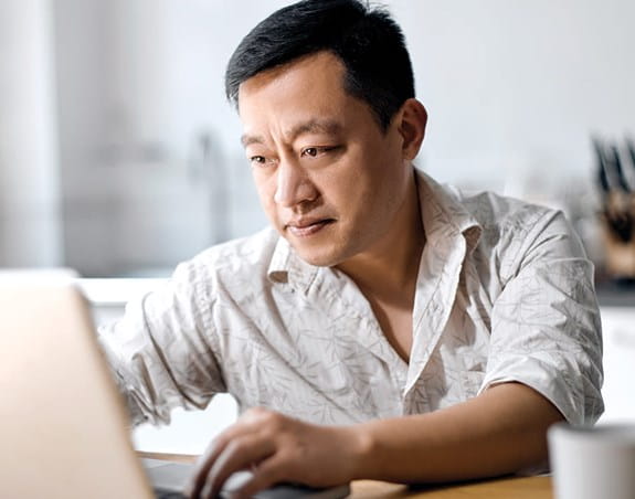 A person looking at a laptop in a kitchen