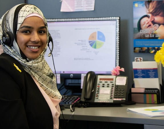 A donor services employee at her desk wearing a head set