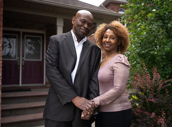 Anthony, héros d’histoires de la SCC, tient la main de son épouse devant leur maison
