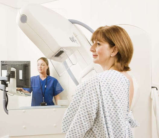 Une patiente en jaquette sur le point de passer une mammographie