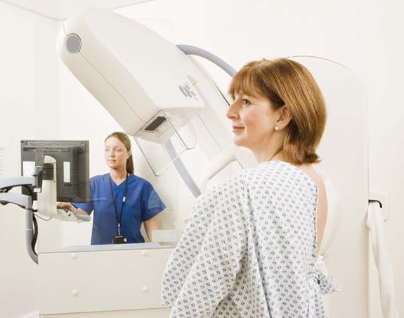 Une patiente en jaquette sur le point de passer une mammographie