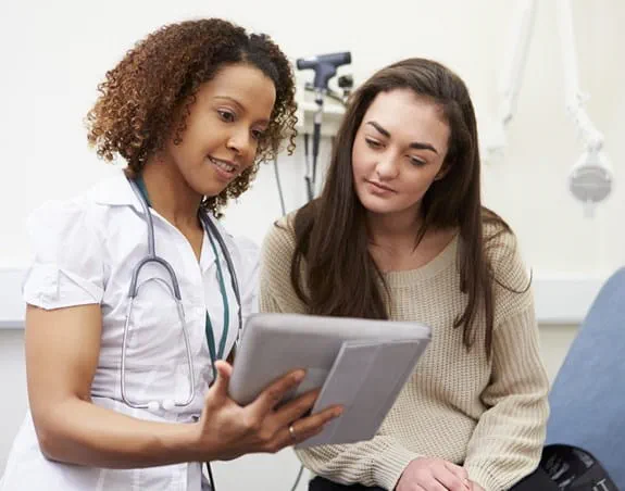 Une patiente et une professionnelle de la santé en train de regarder quelque chose sur une tablette