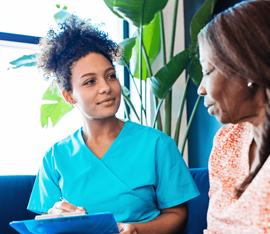 Healthcare professional writing on a clipboard with a patient in a clinic waiting room