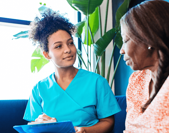 Healthcare professional writing on a clipboard with a patient in a clinic waiting room