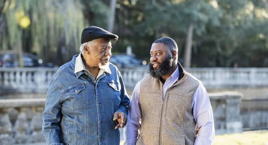 A Black father and son walking in a park.
