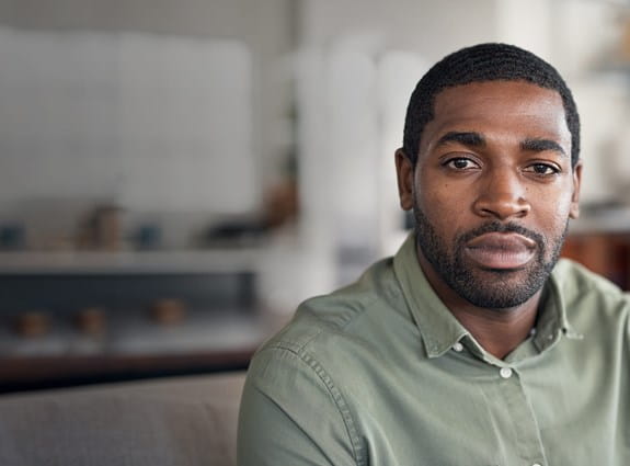 A young black man sitting in his home.